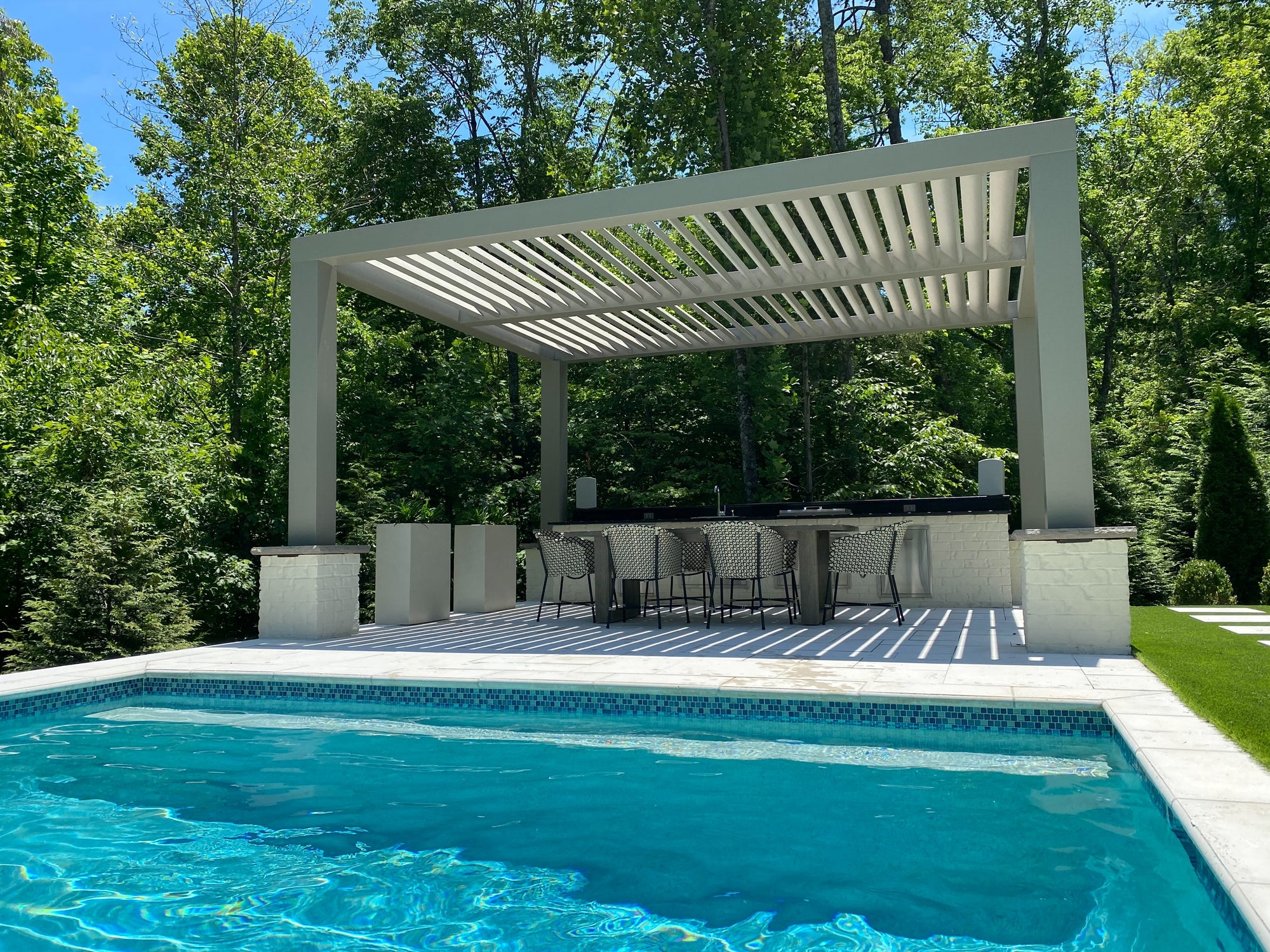 Solace customizable fiberglass pergola with louvered rafters over an outdoor kitchen
