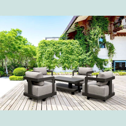 Outdoor patio furniture set on a wooden deck with greenery and a building in the background