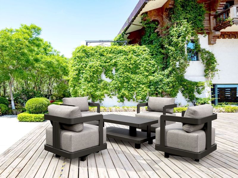 Outdoor patio furniture set on a wooden deck with greenery and a building in the background