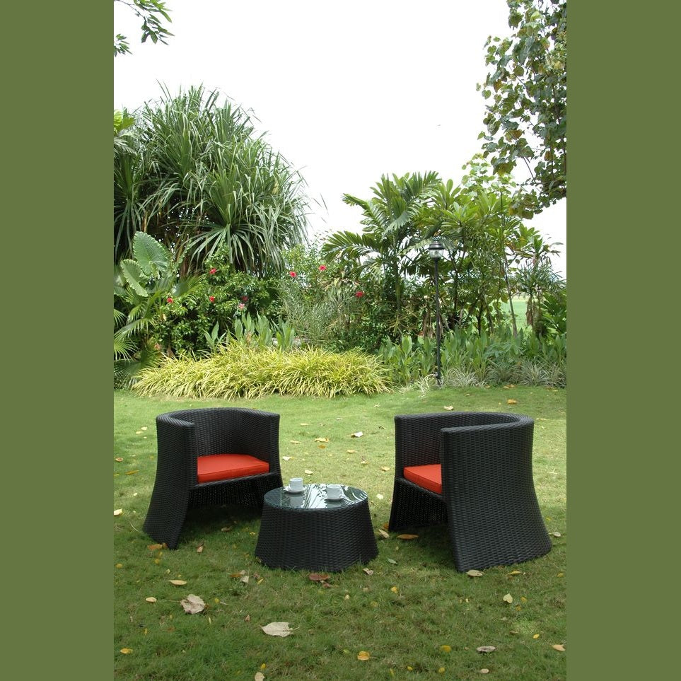 Outdoor furniture set with black chairs and a table on grass, surrounded by greenery.