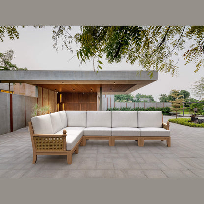 Outdoor patio with a wooden sectional sofa on a stone patio
