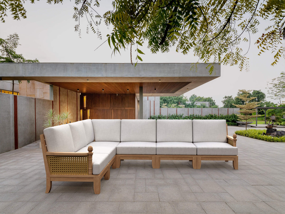 Outdoor patio with a wooden sectional sofa on a stone patio
