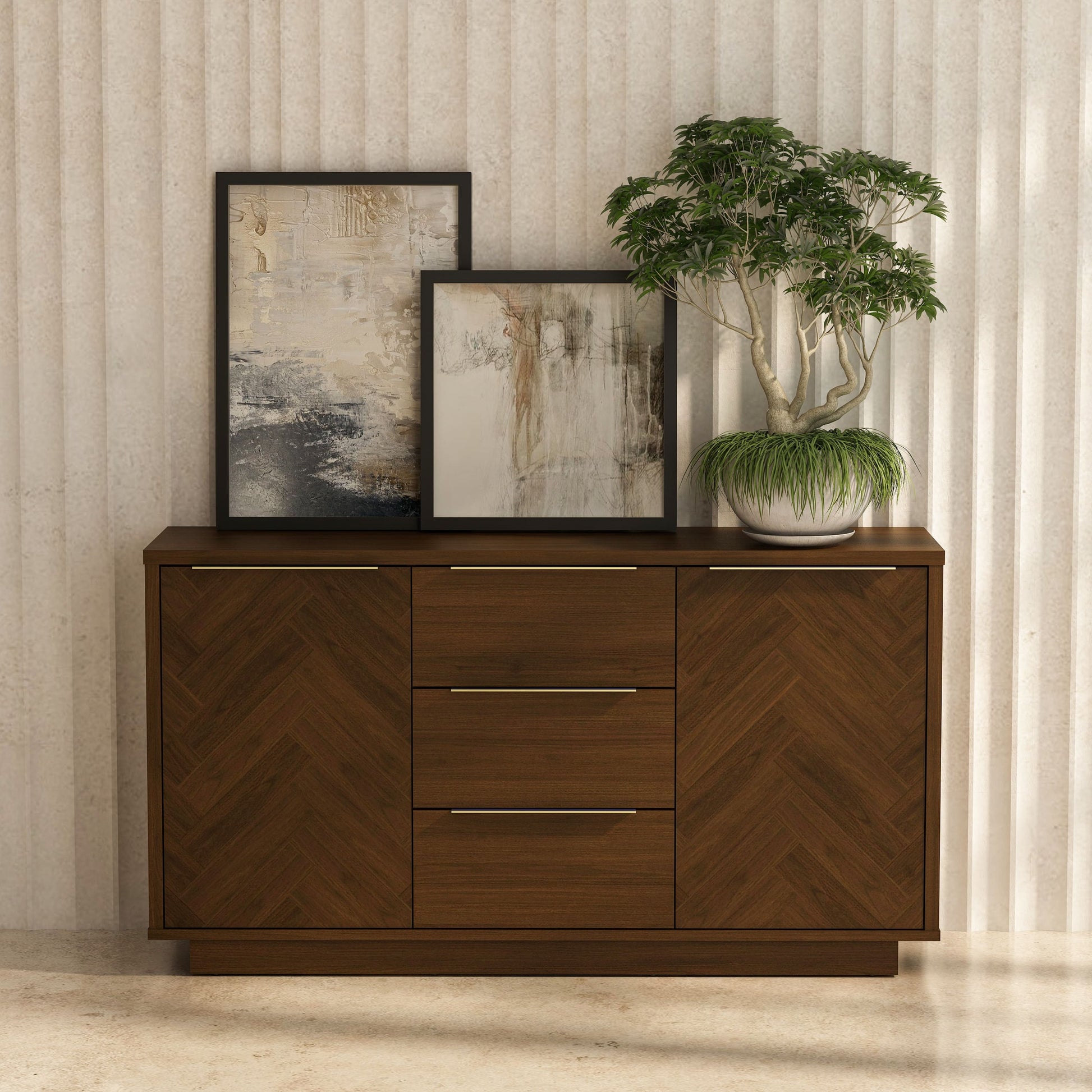 Wooden sideboard with chevron pattern, two framed artworks, and a potted plant against a neutral wall.