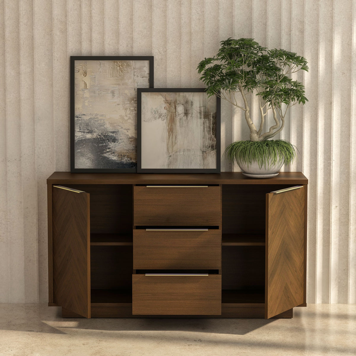 Wooden sideboard with two framed artworks and a potted plant against a textured wall.
