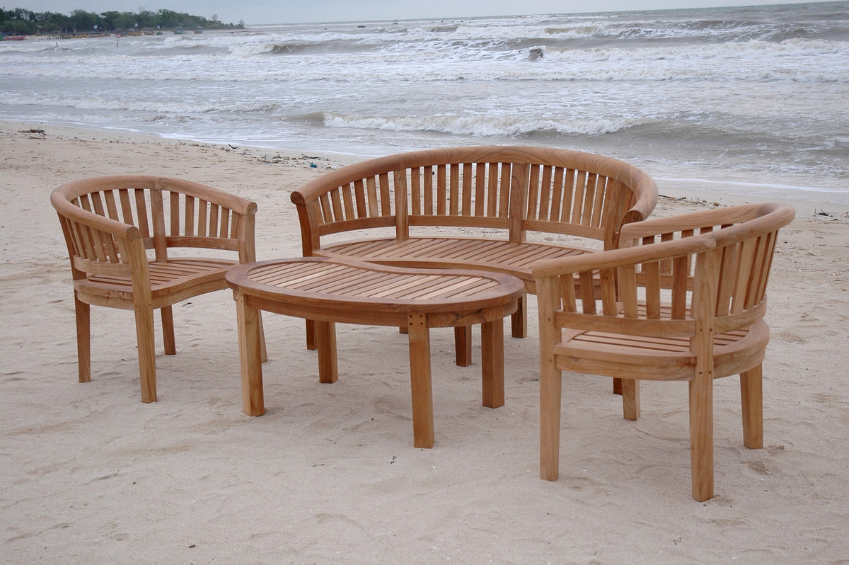 Wooden outdoor furniture set on a sandy beach with ocean waves in the background
