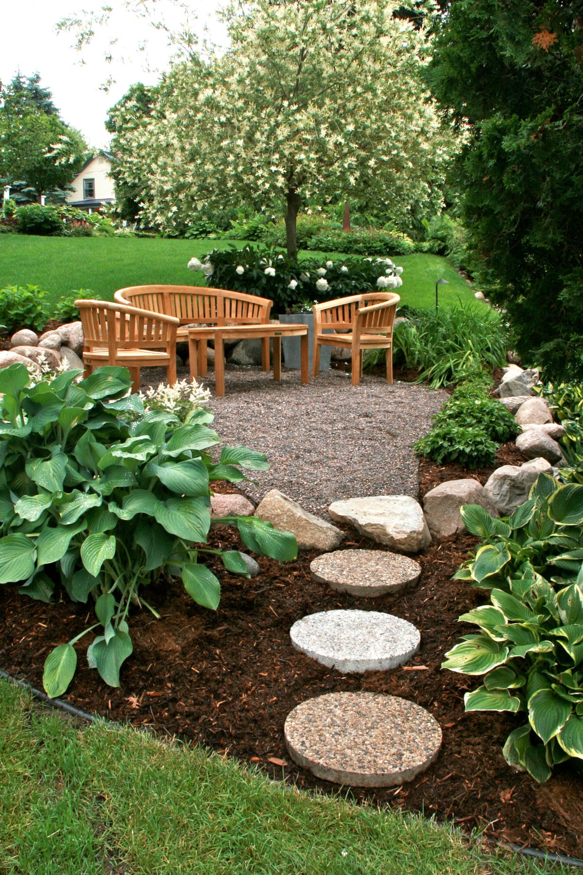 Garden with wooden bench, stone pathway, and greenery