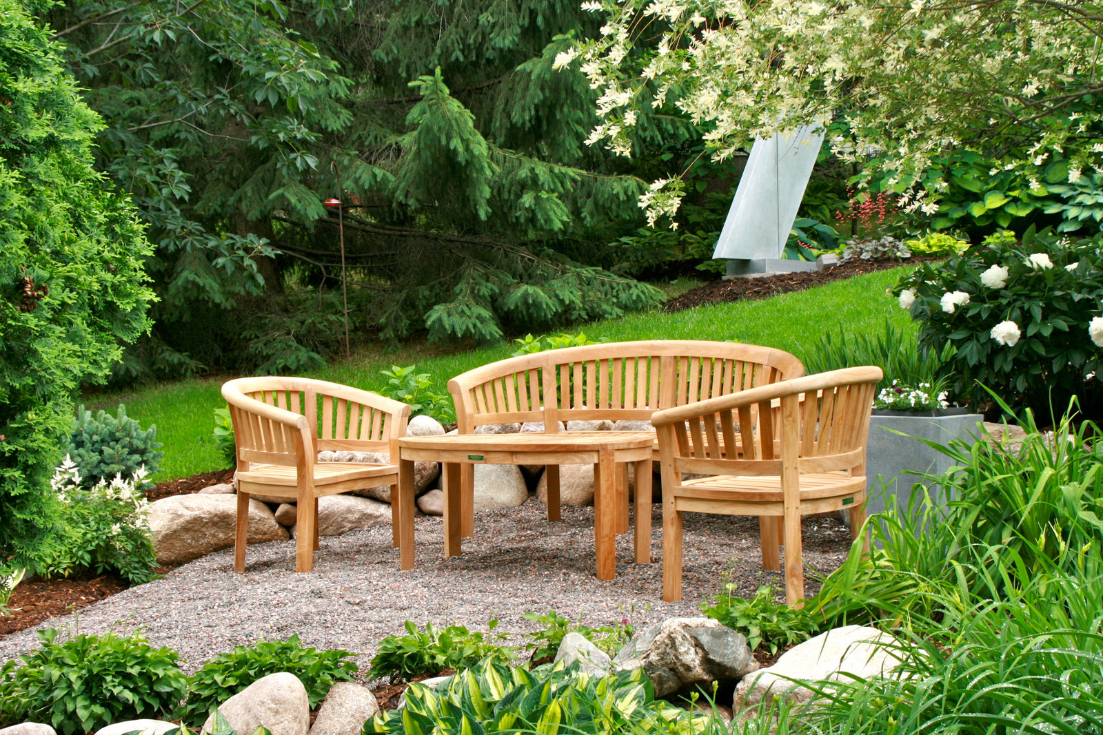 Wooden garden furniture set in a lush garden setting with trees and plants.