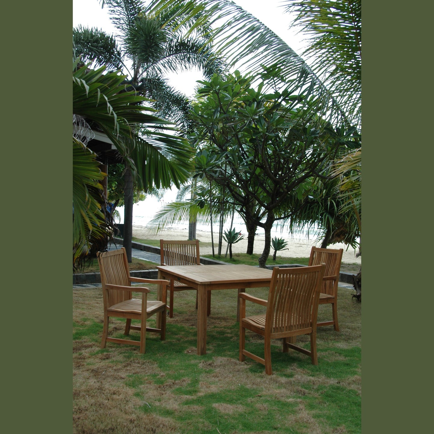 Wooden outdoor dining set with chairs on a grassy area near palm trees and a beach.