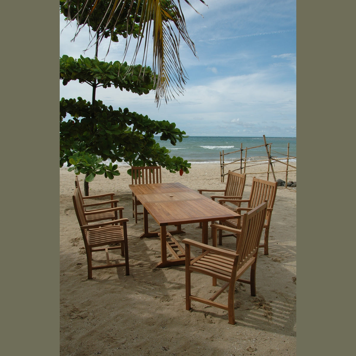 Wooden dining set on a sandy beach with ocean and sky in the background
