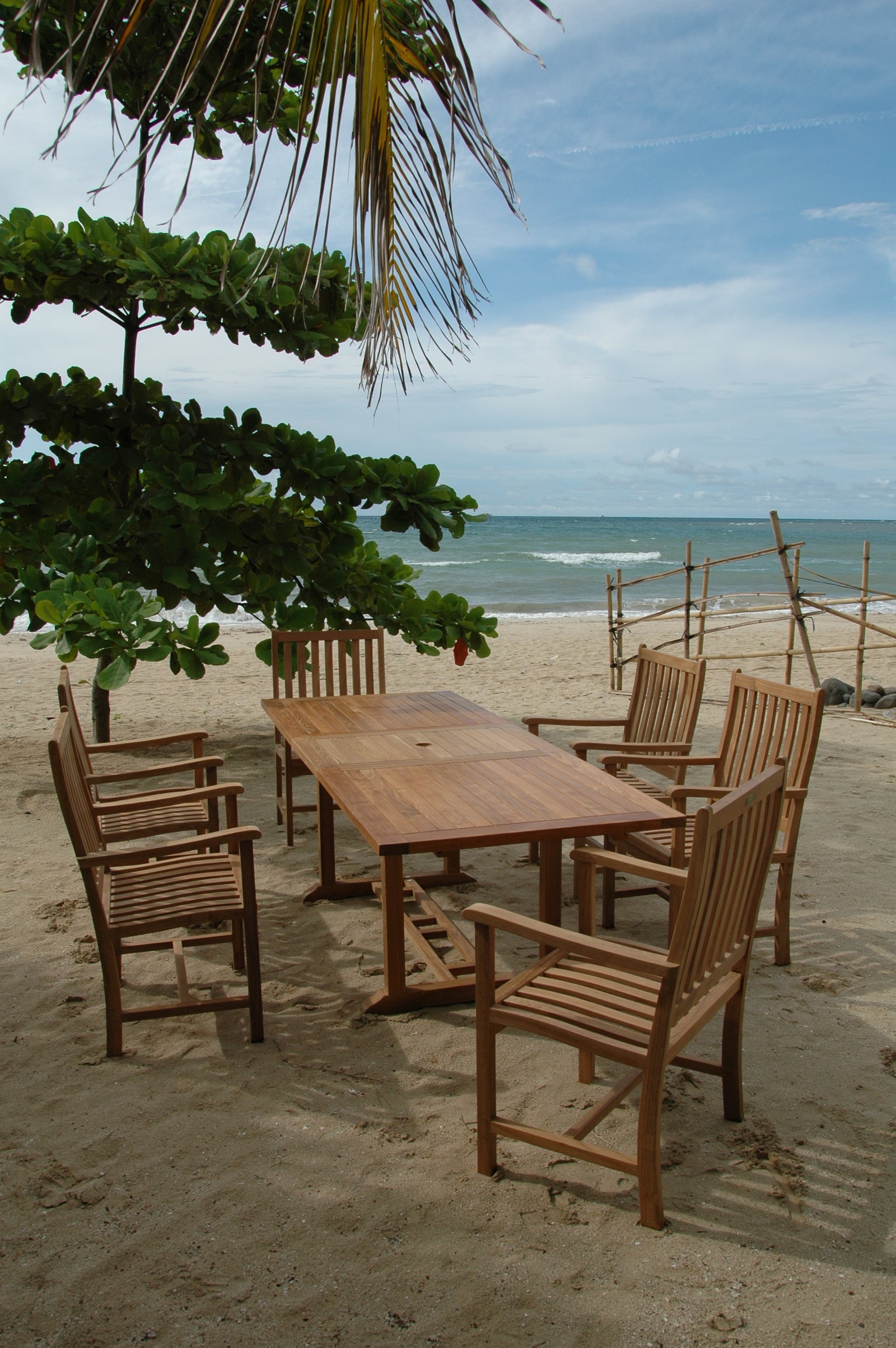 Wooden dining set on a sandy beach with ocean and sky in the background