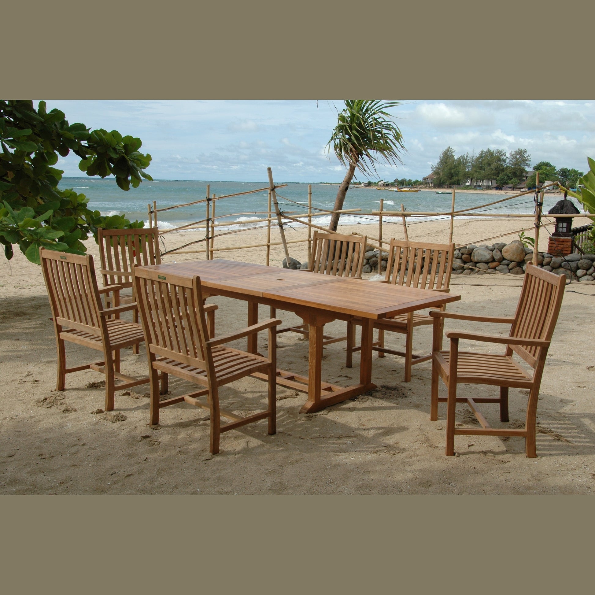Wooden outdoor dining set on a sandy beach with ocean view