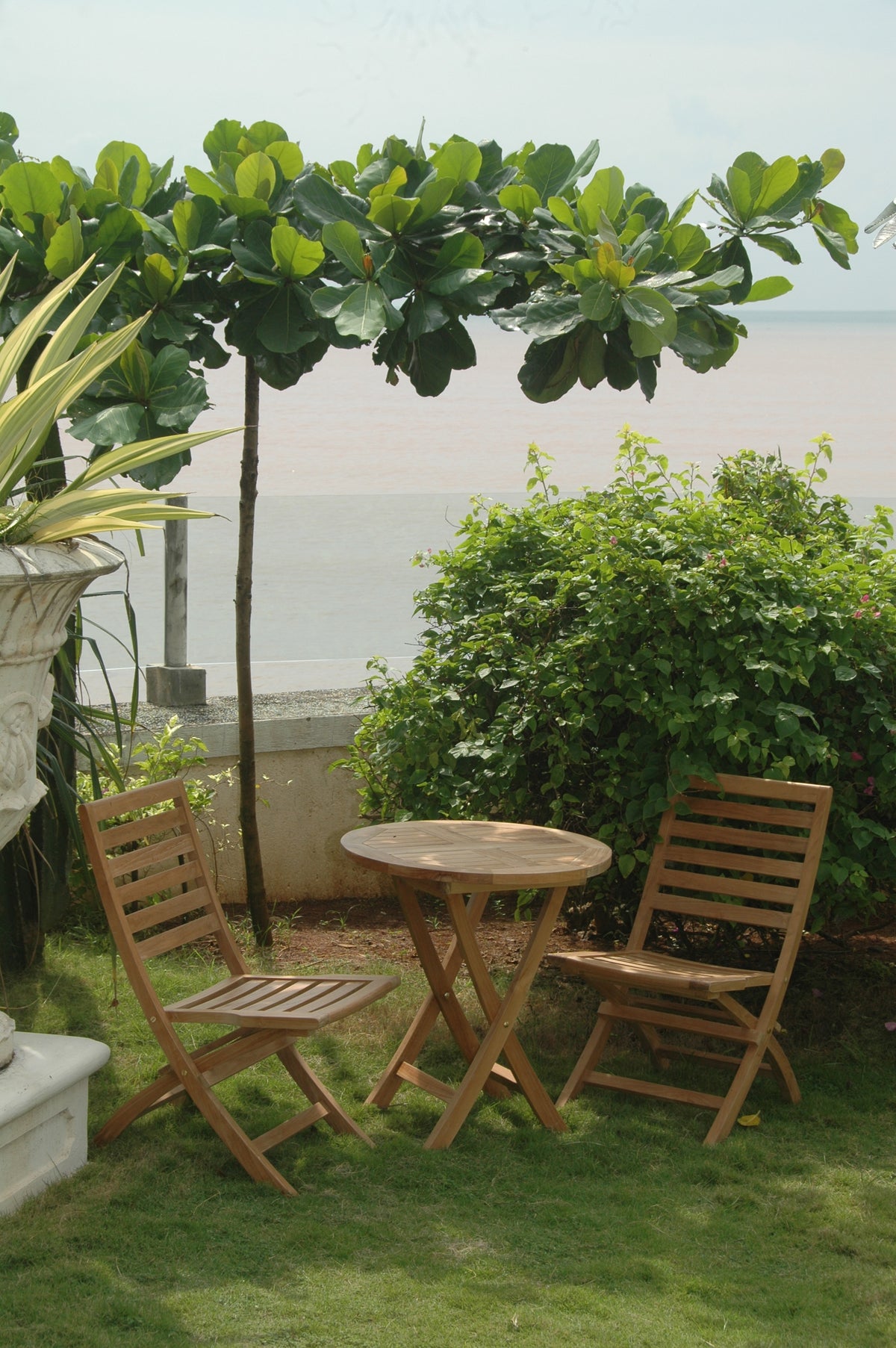 Wooden outdoor table and chairs with a scenic view of water and greenery.