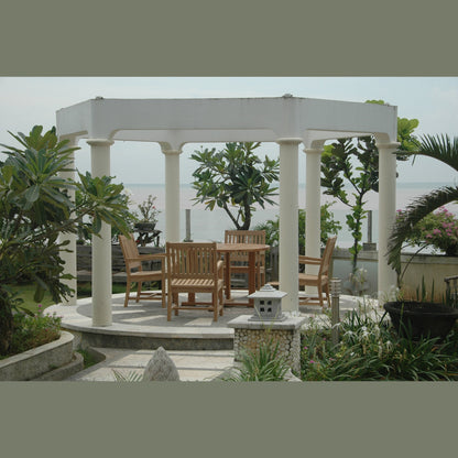 Patio with wooden furniture under a white pergola surrounded by greenery.