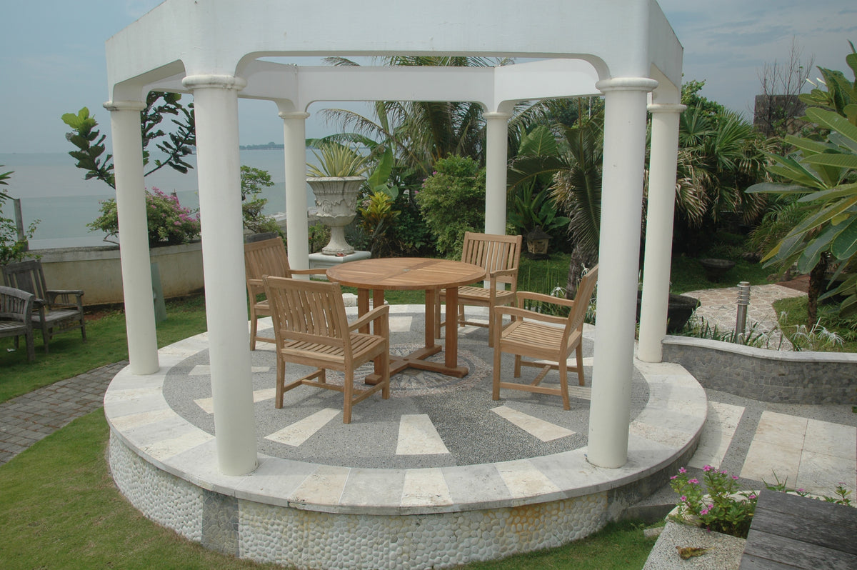 Gazebo with wooden furniture on a patio area by a body of water.