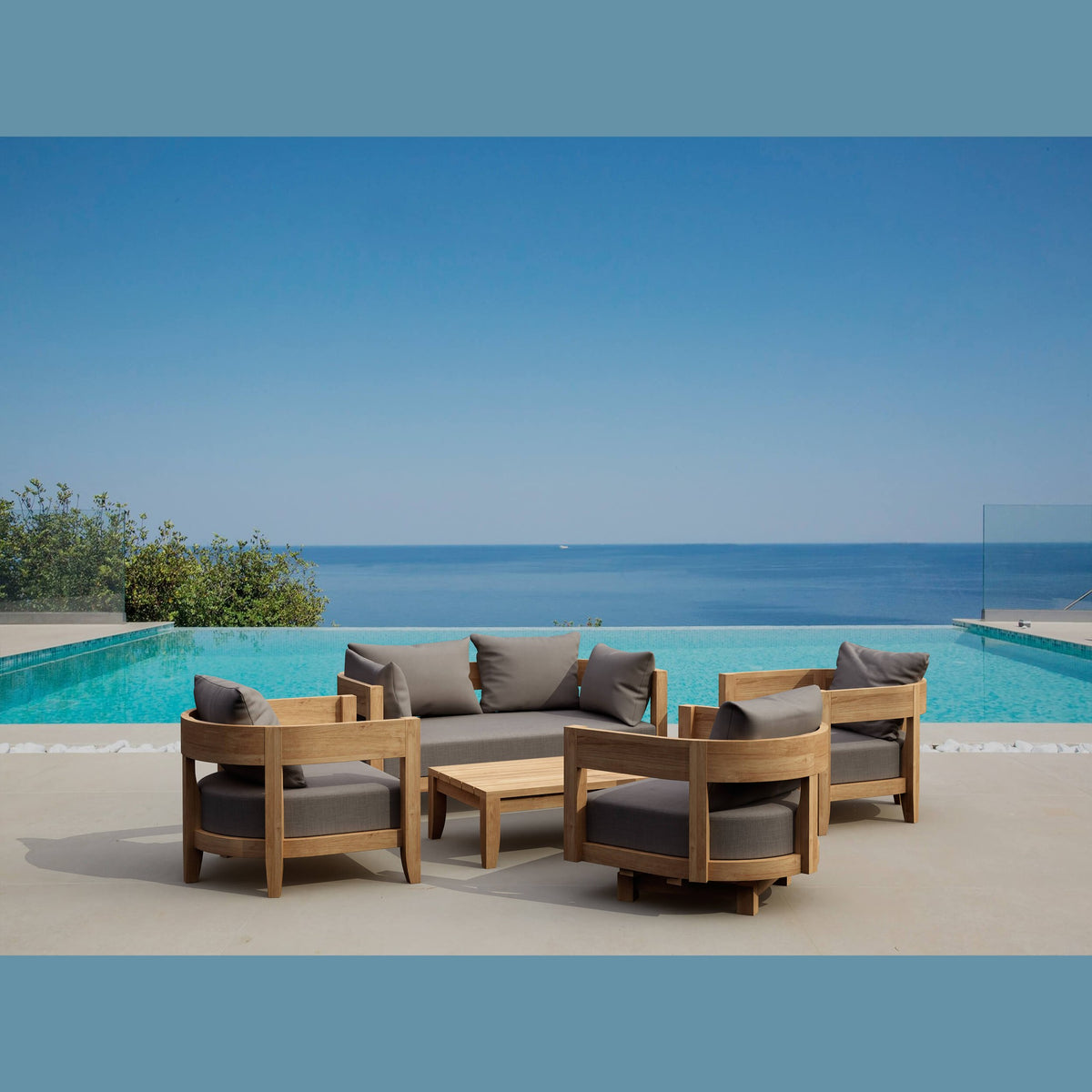 Outdoor furniture set with gray cushions by a pool with ocean view
