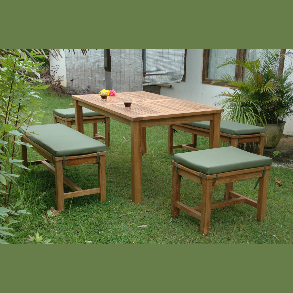 Wooden outdoor dining set with green cushions on a grassy area.