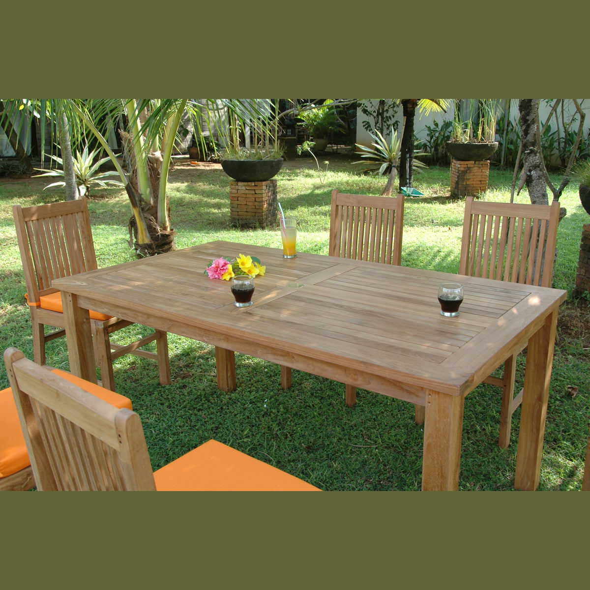 Wooden outdoor dining table with chairs and drinks on a grassy area