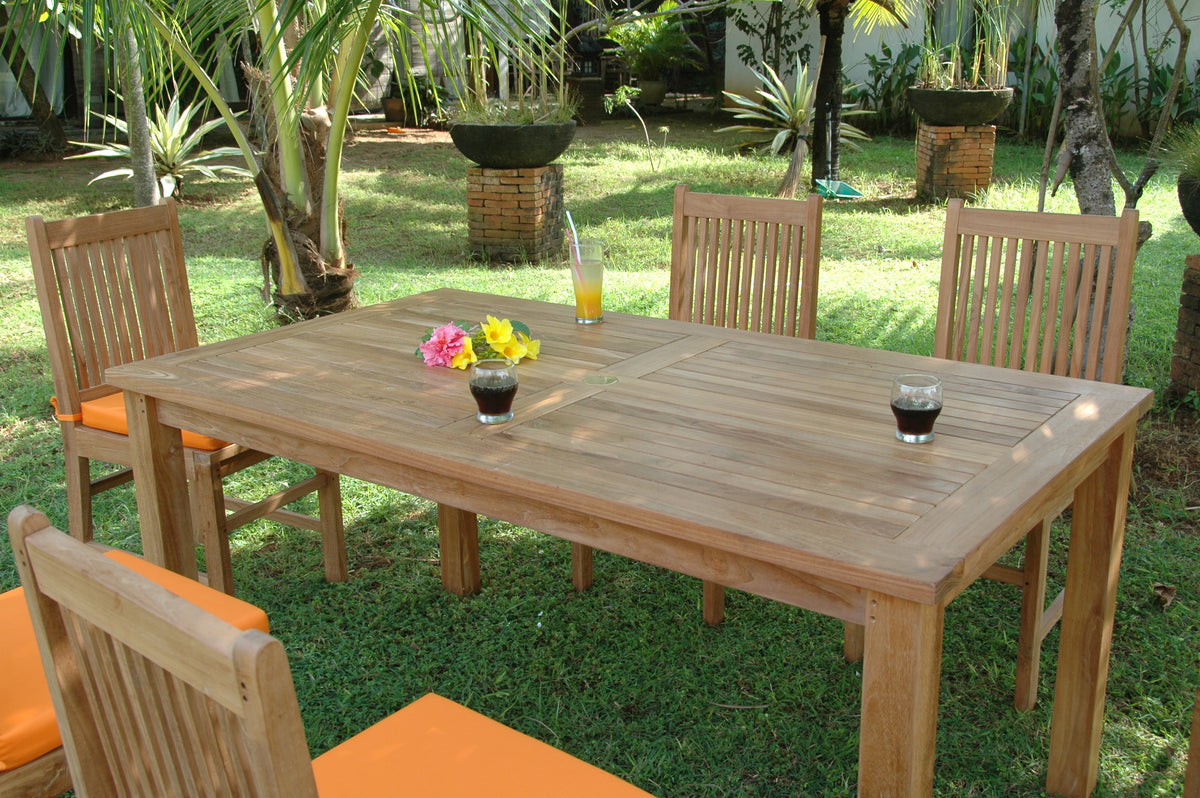 Wooden outdoor dining table with chairs and drinks on a grassy area