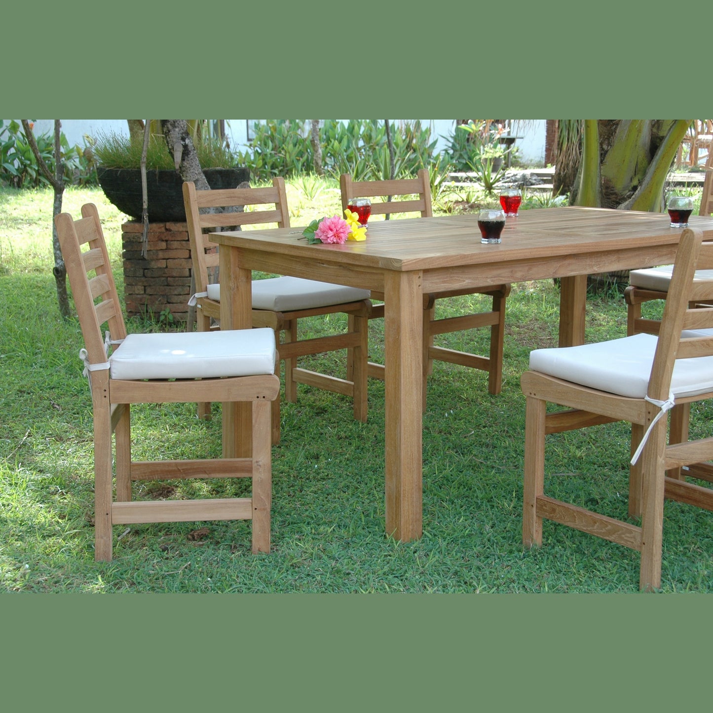 Wooden outdoor dining table with chairs and cushions on a grassy area
