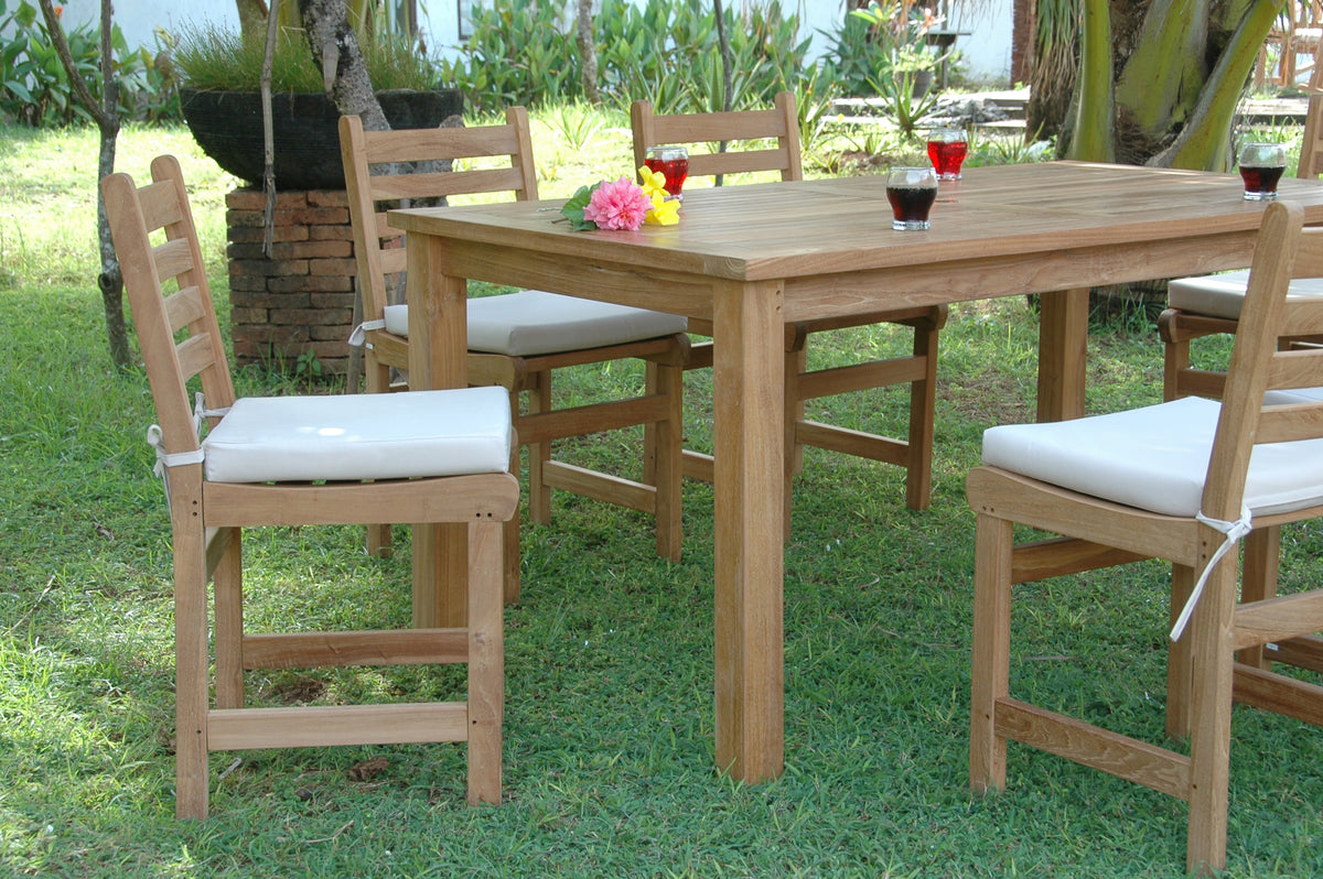 Wooden outdoor dining table with chairs and cushions on a grassy area