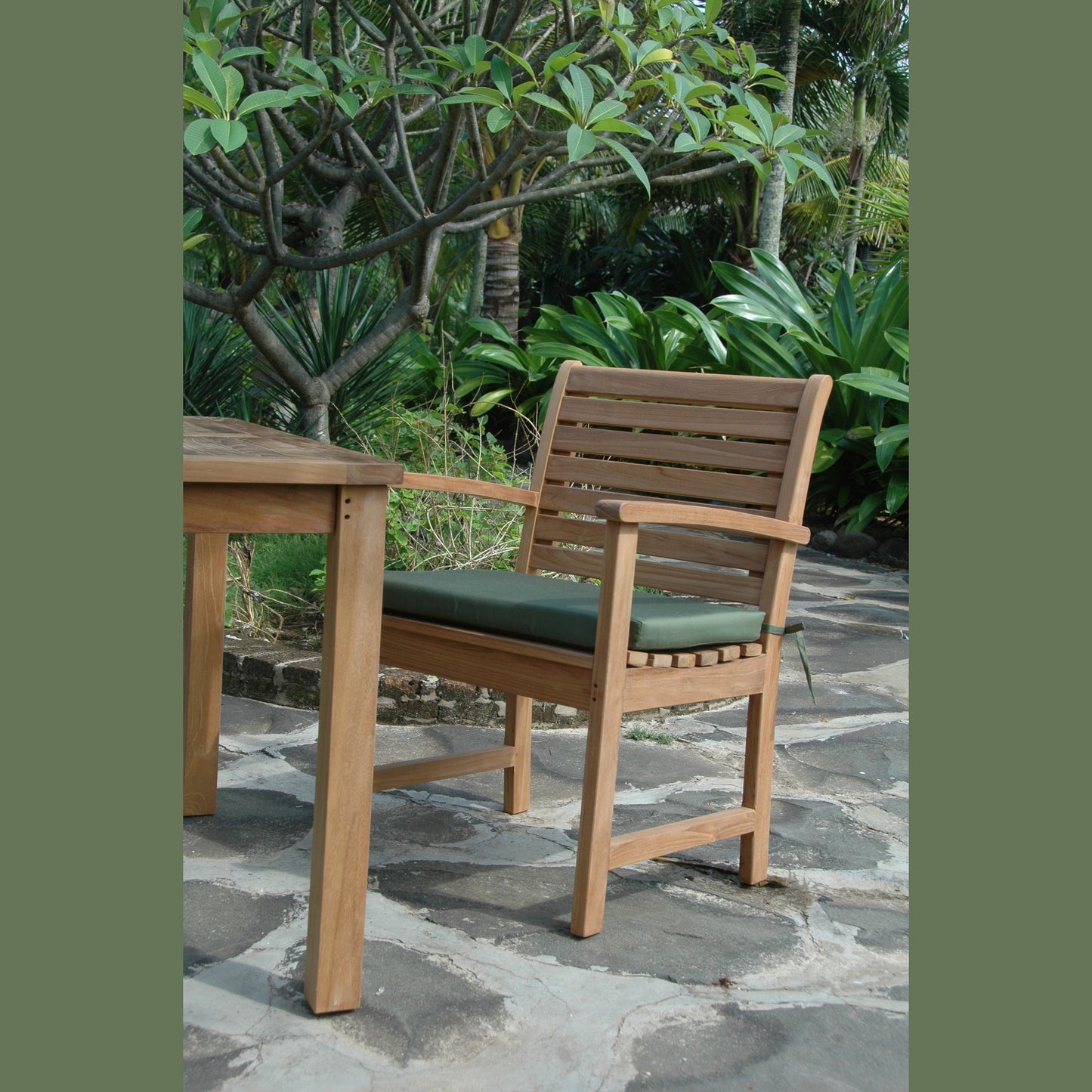 Wooden chair against a stone wall with greenery in the background
