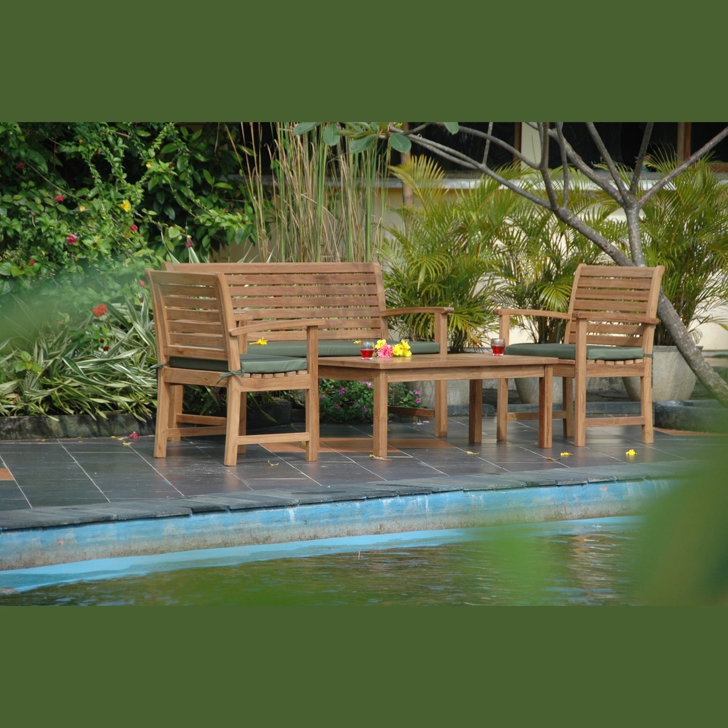 Wooden outdoor furniture set by a pool with plants in the background