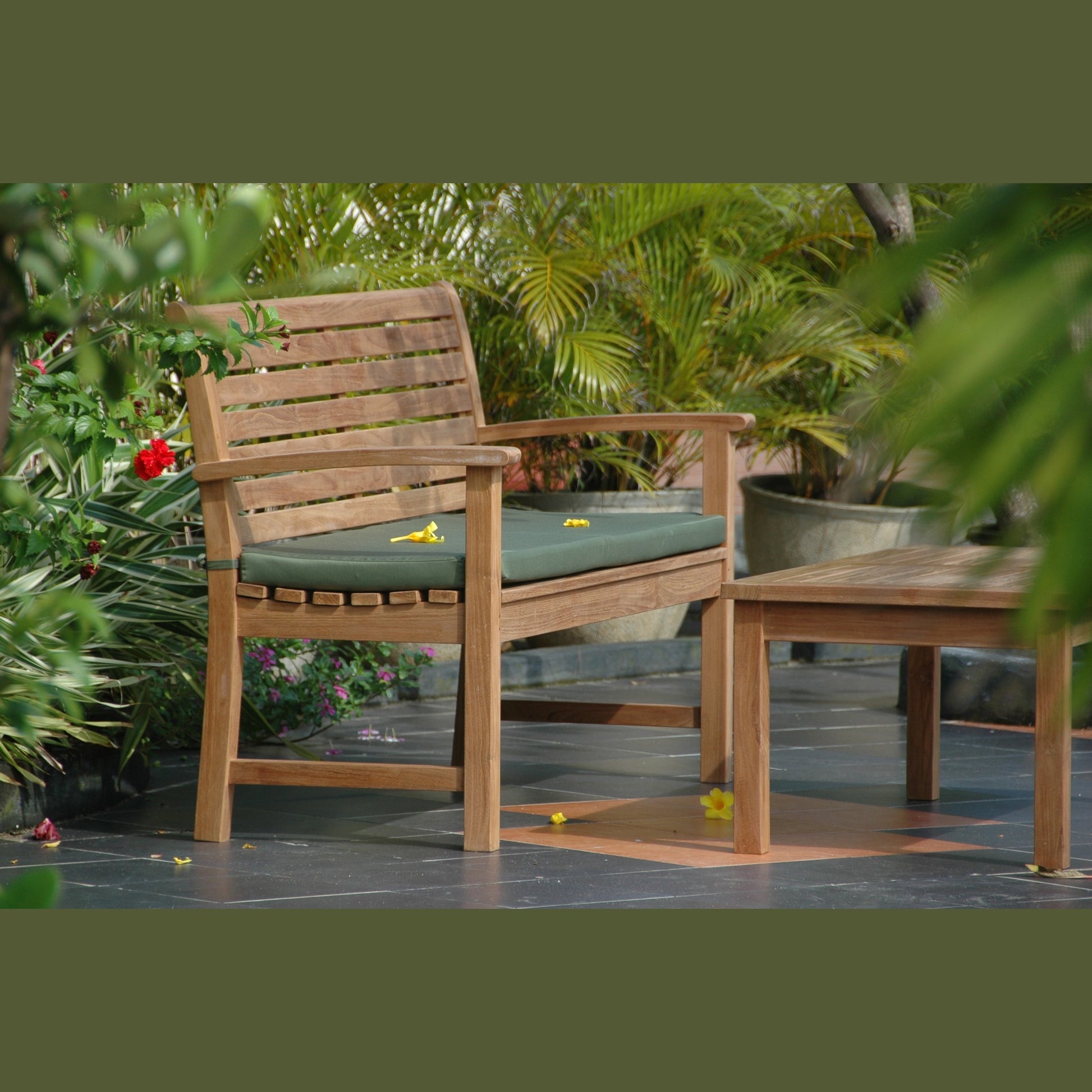 Wooden outdoor bench with green cushion on a patio surrounded by plants