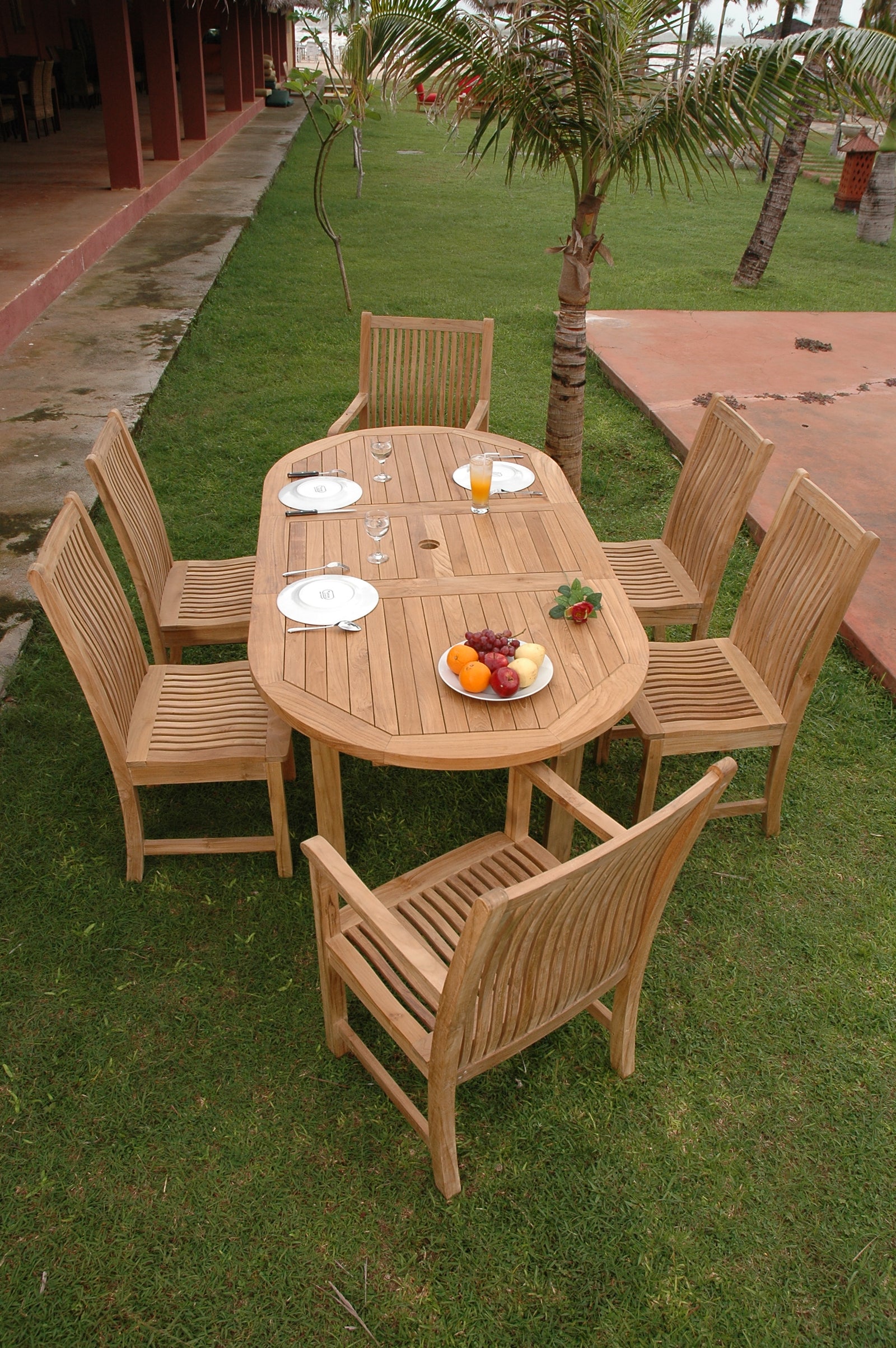 Wooden outdoor dining set with table and chairs on a grassy area.
