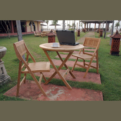 Wooden outdoor table with chairs and a laptop on a grassy area.