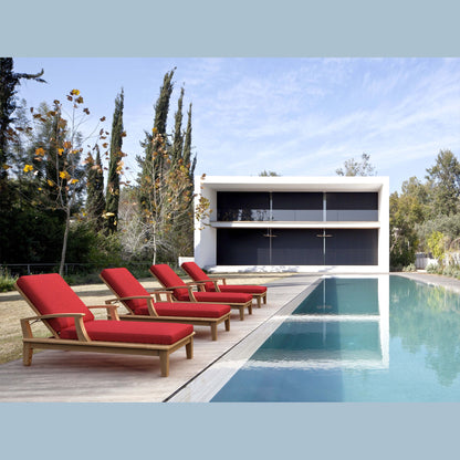 Red lounge chairs by a pool with a modern house in the background