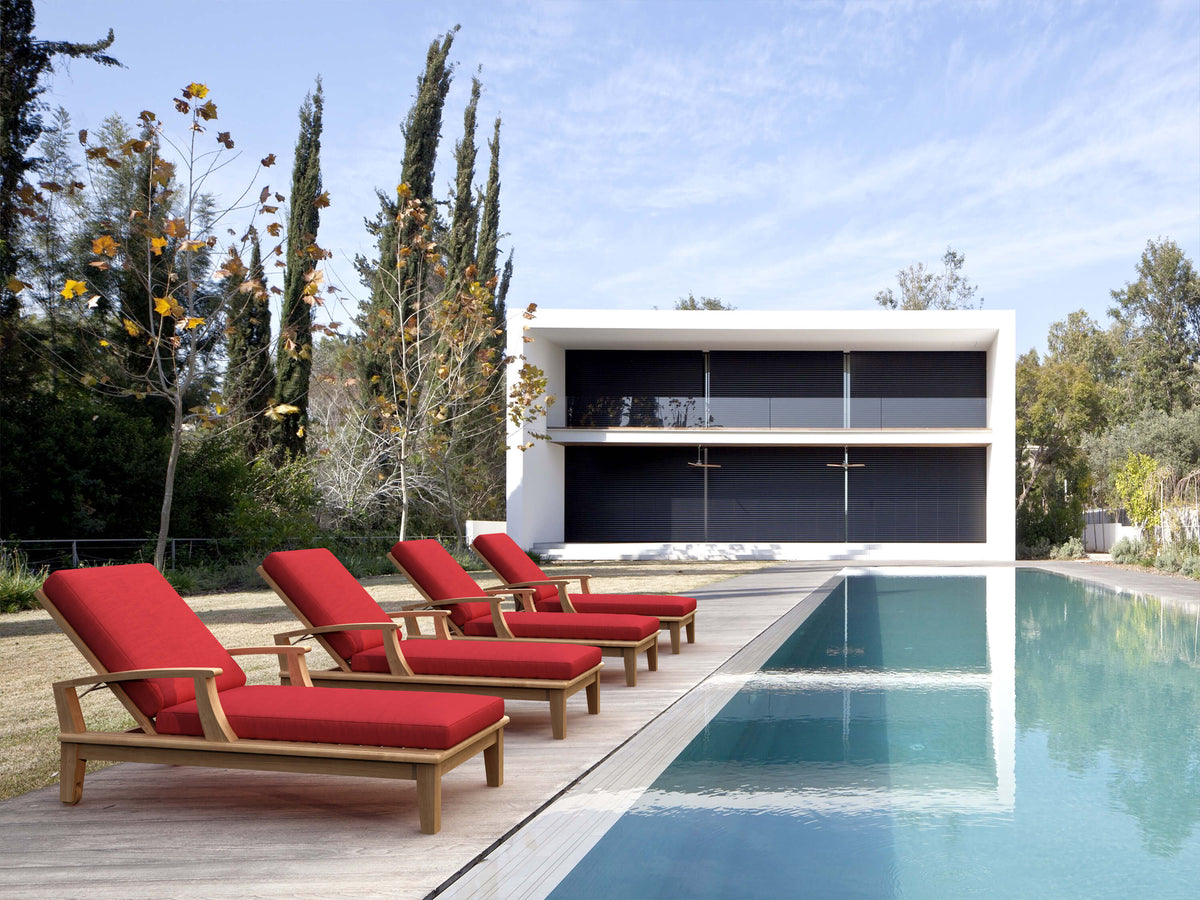 Red lounge chairs by a pool with a modern house in the background