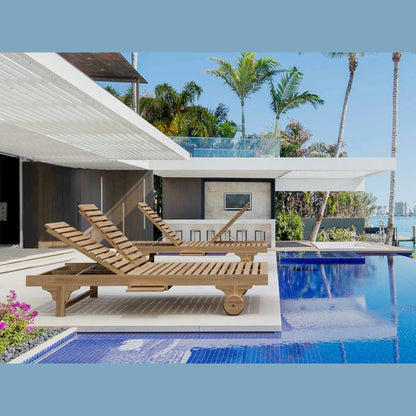 Wooden lounge chairs by a pool with palm trees and a clear sky