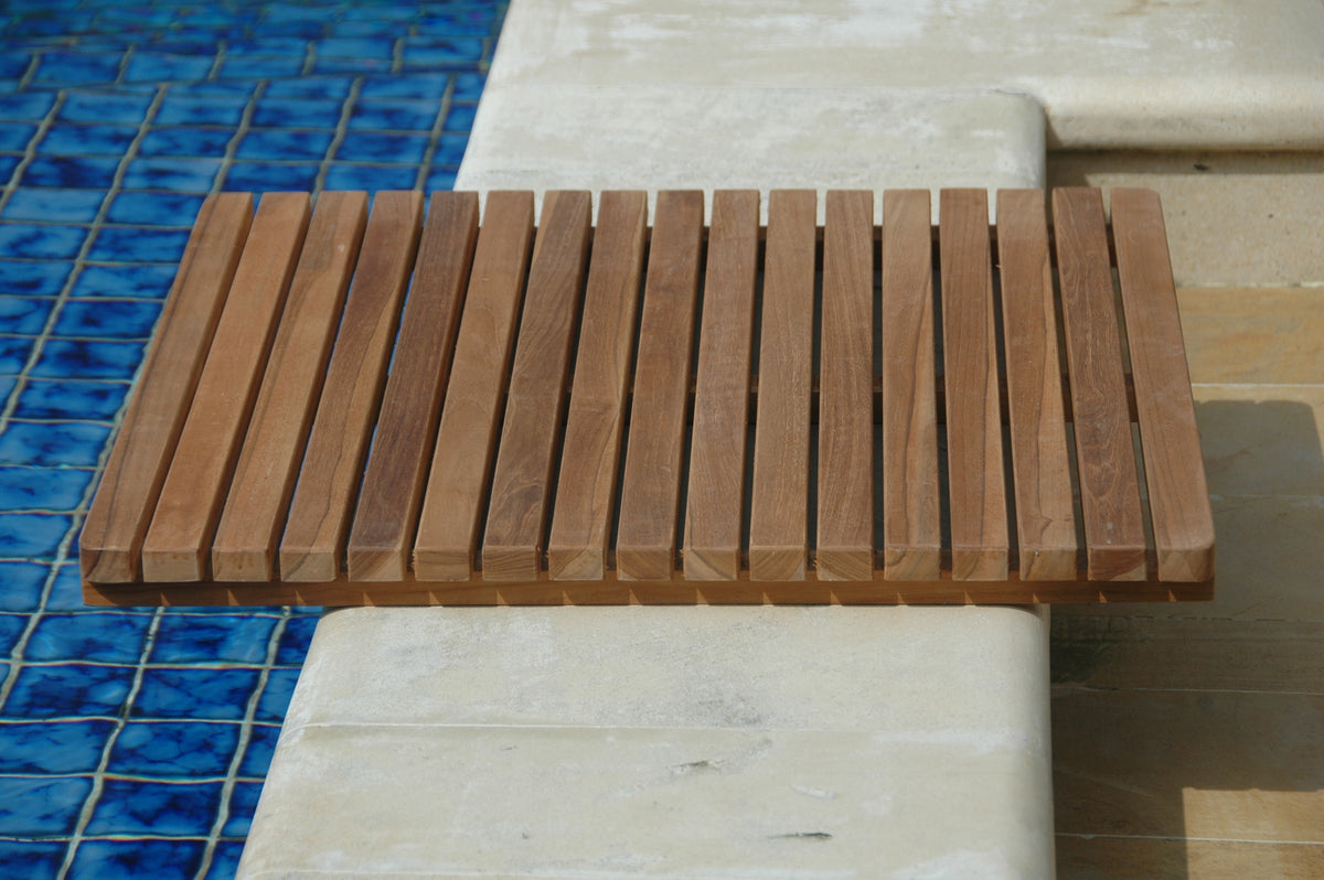Wooden bench with slatted design on a tiled floor next to a pool.