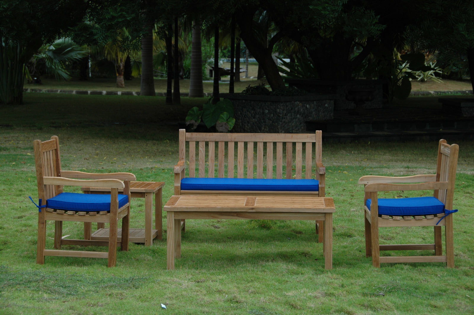 Wooden outdoor furniture set with blue cushions on a grassy area