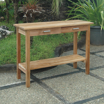 Wooden console table with drawers on a stone patio with greenery in the background