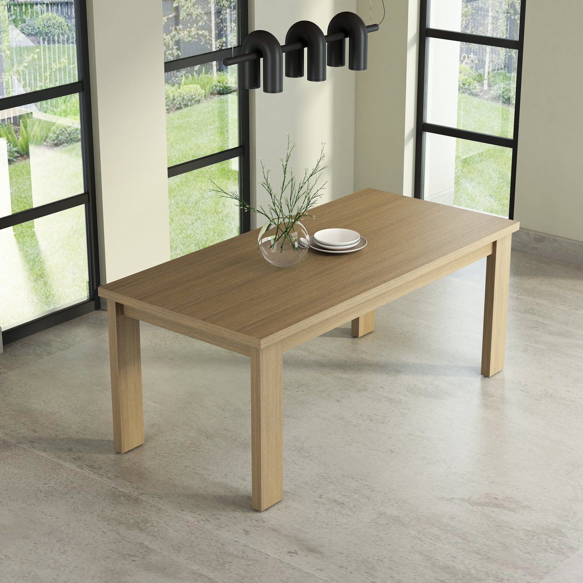 Wooden dining table with a vase and plates in a room with large windows.