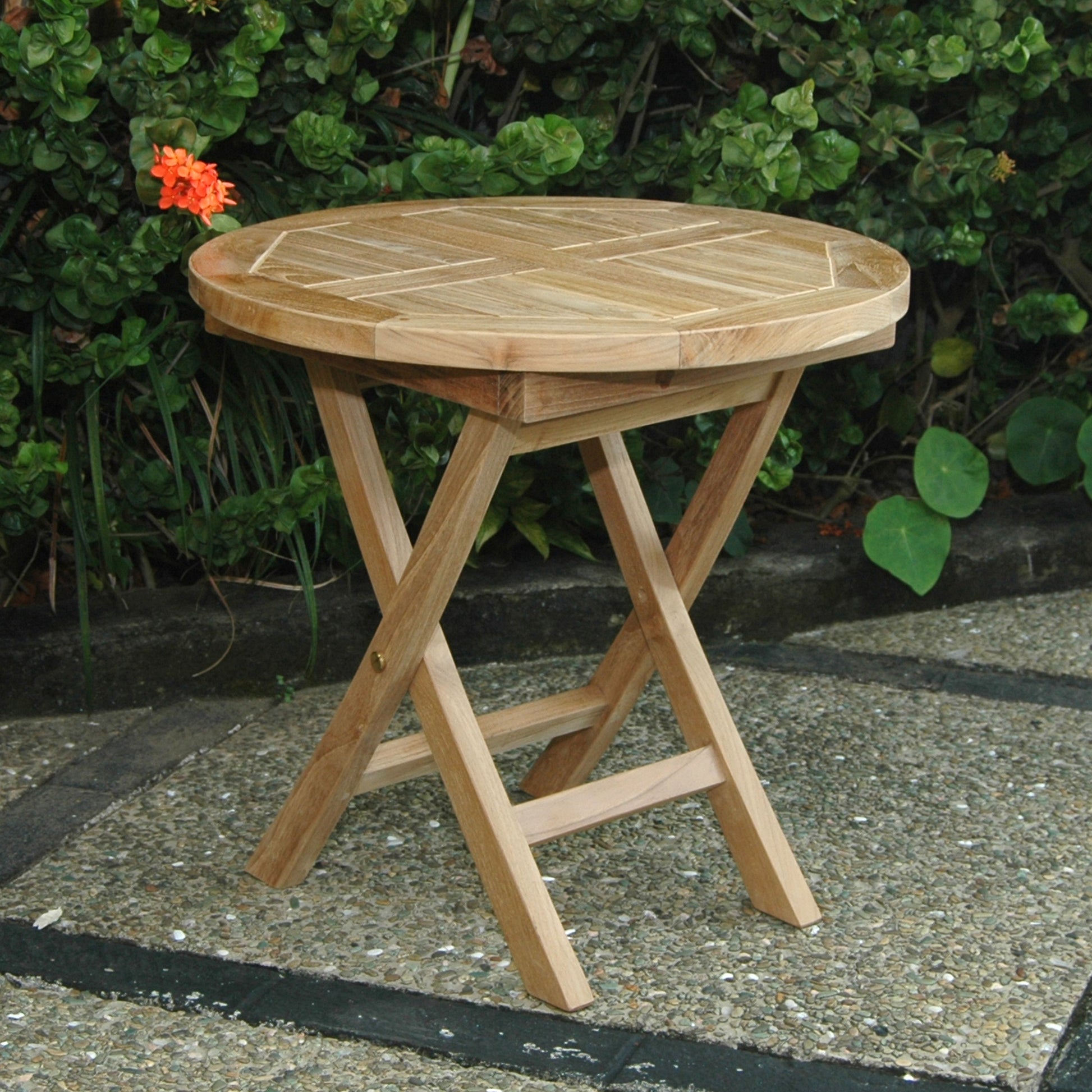 Wooden folding table outdoors with greenery in the background