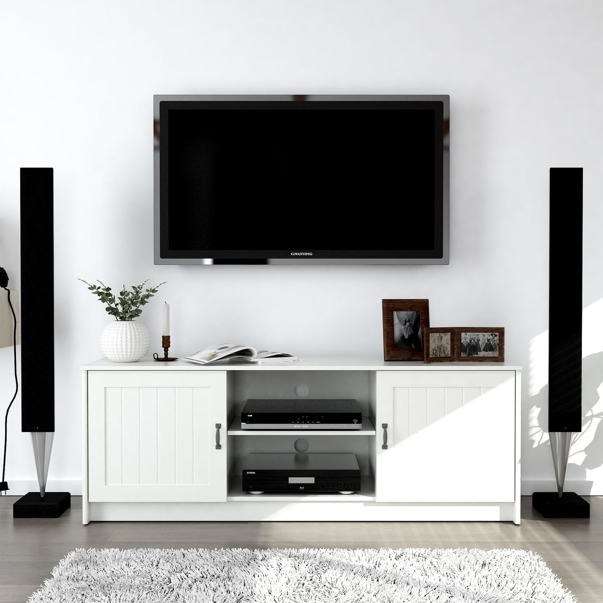 Modern living room setup with a TV mounted on the wall, white entertainment console, and speakers.