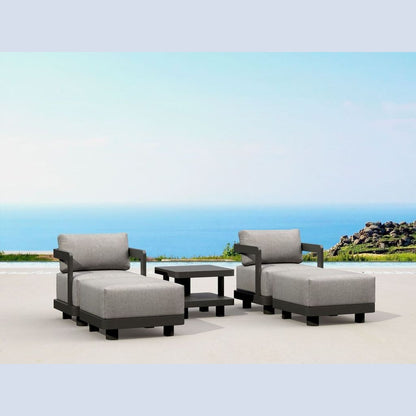 Outdoor patio furniture set with gray cushions on a sandy beach with ocean view.