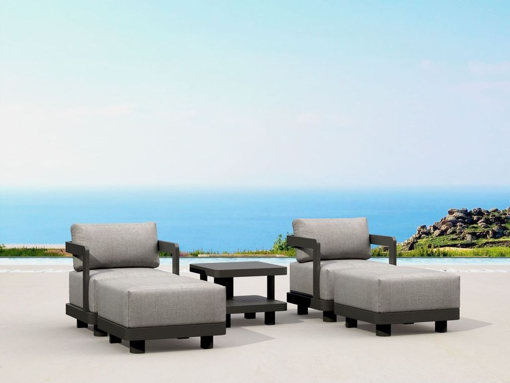 Outdoor patio furniture set with gray cushions on a sandy beach with ocean view.