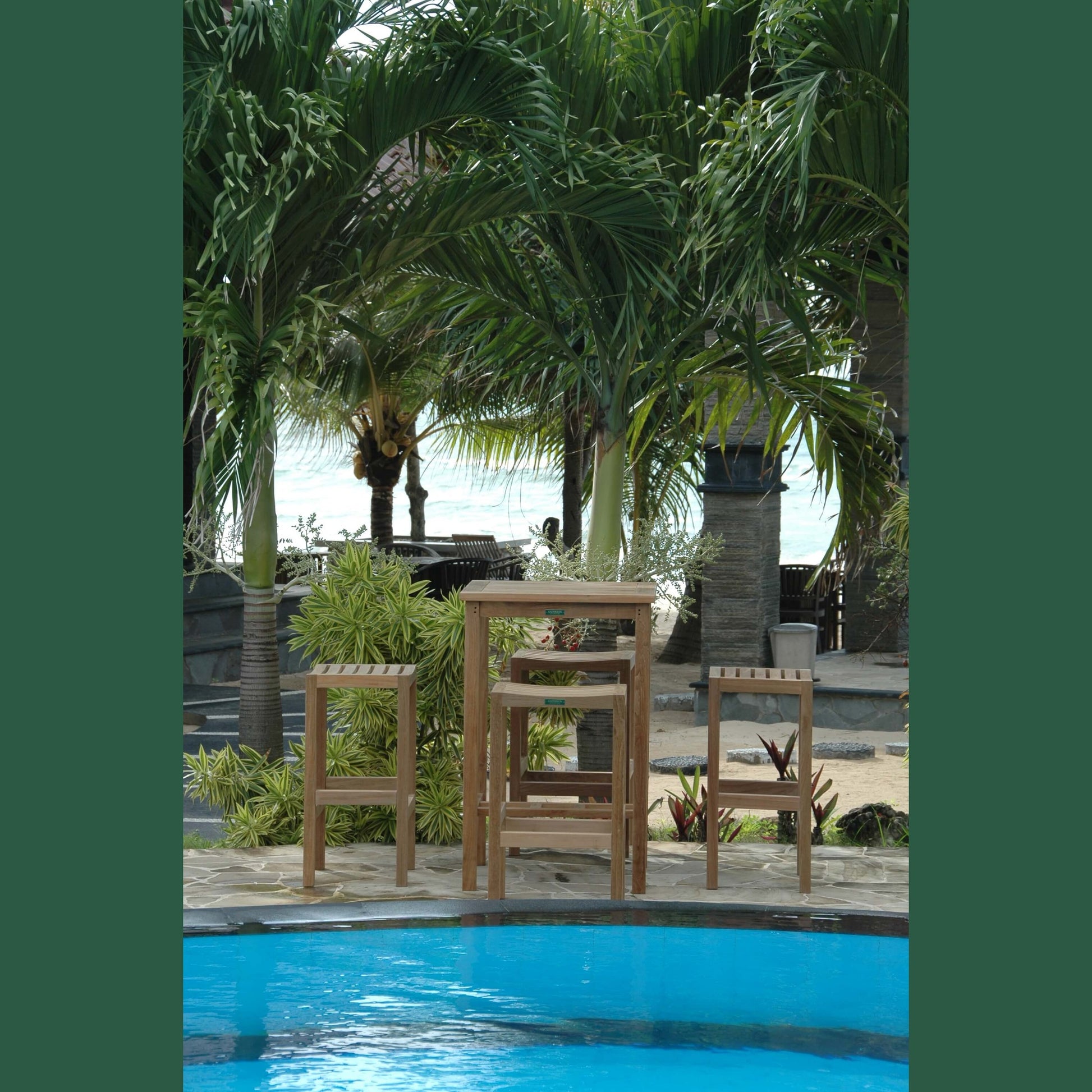 Wooden chairs and table by a poolside with palm trees in the background