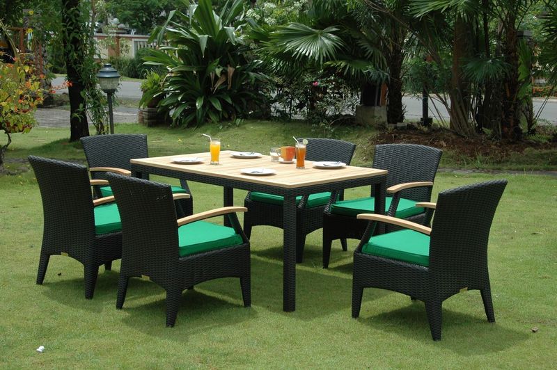 Outdoor dining set with a table and chairs on a grassy area with greenery.