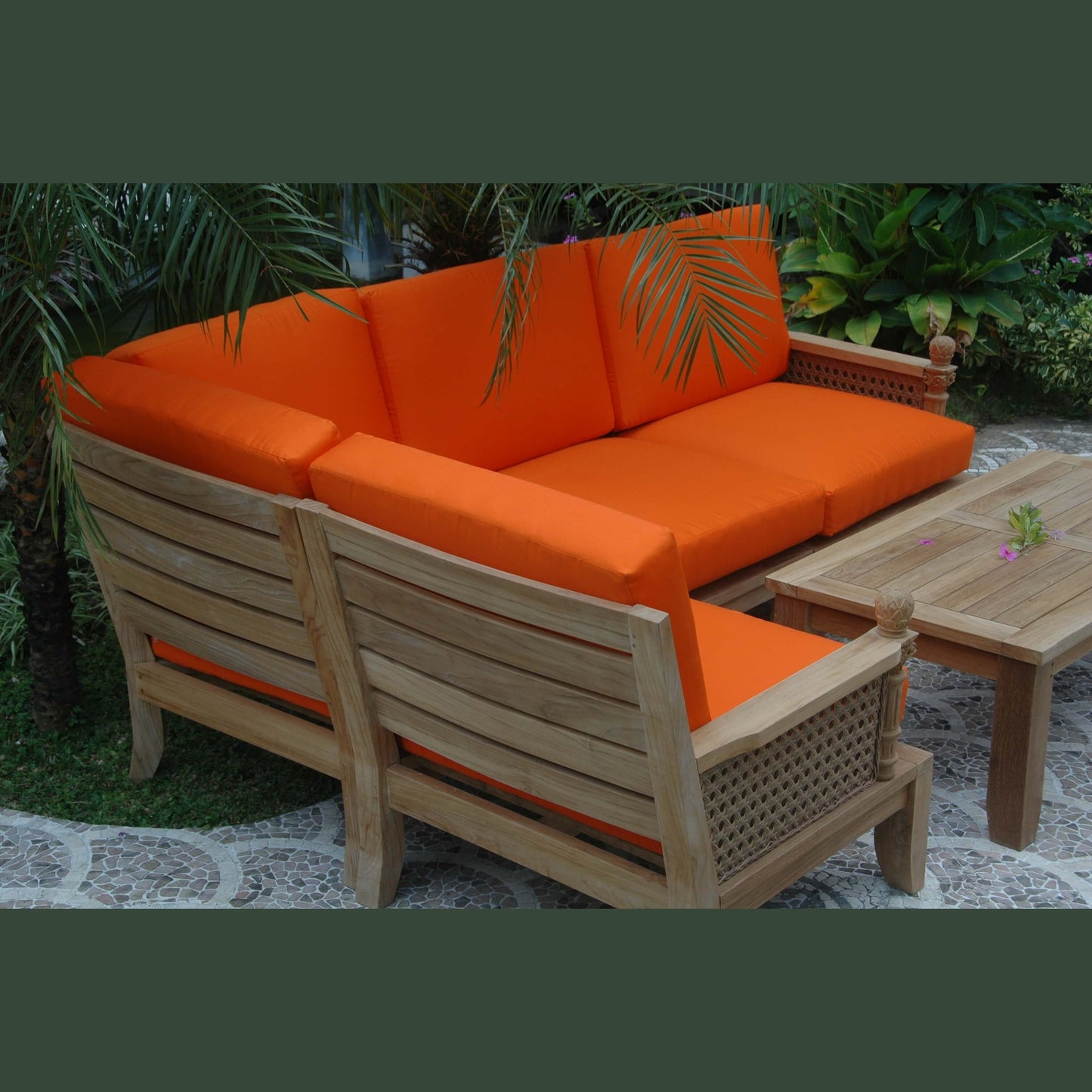 Outdoor furniture set with orange cushions and wooden frame in a garden setting.