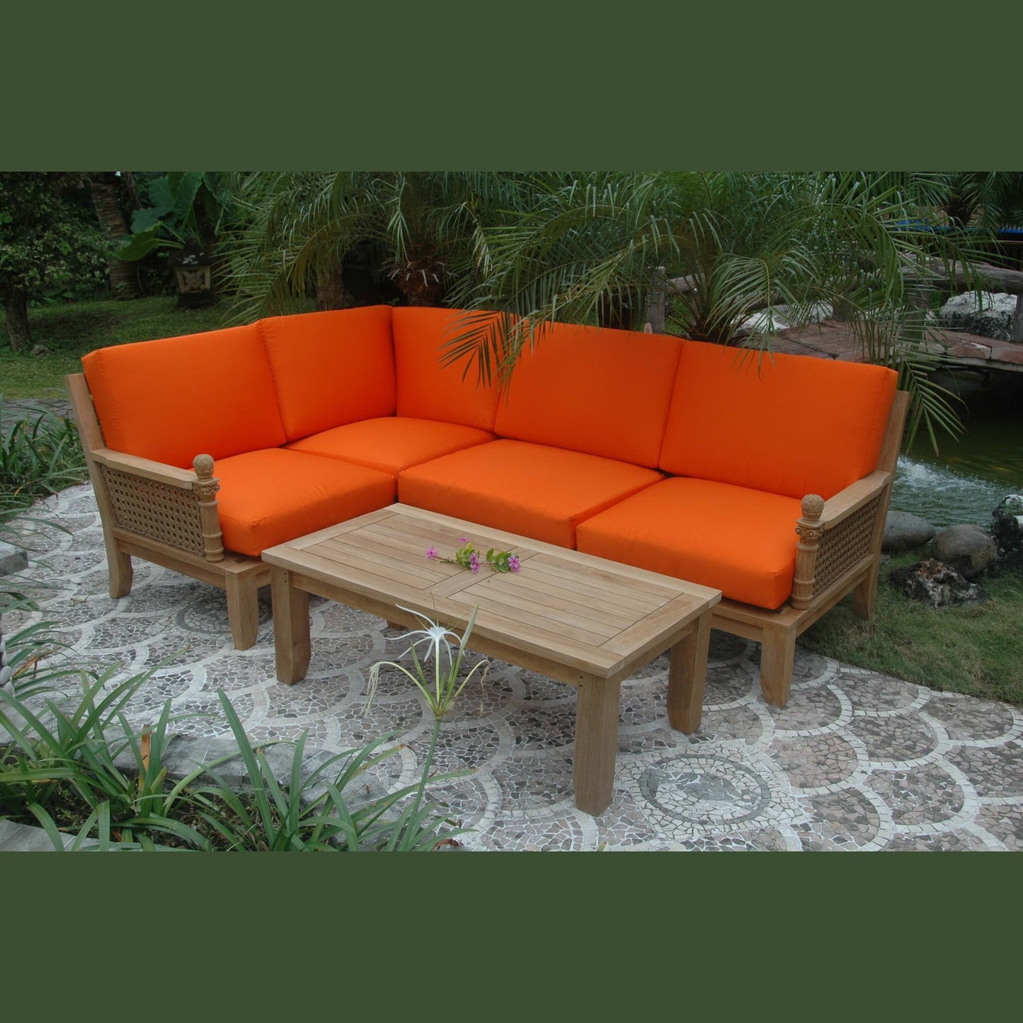 Outdoor patio set with orange cushions and a wooden table in a garden setting.