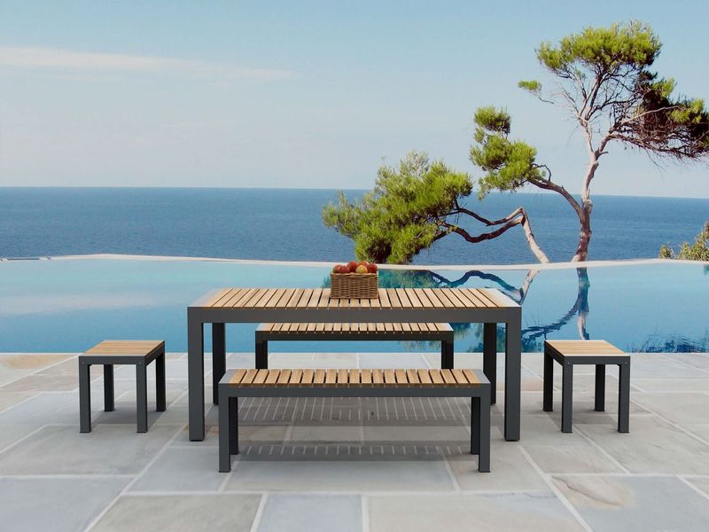 Outdoor furniture set with tables and benches by a pool with ocean view