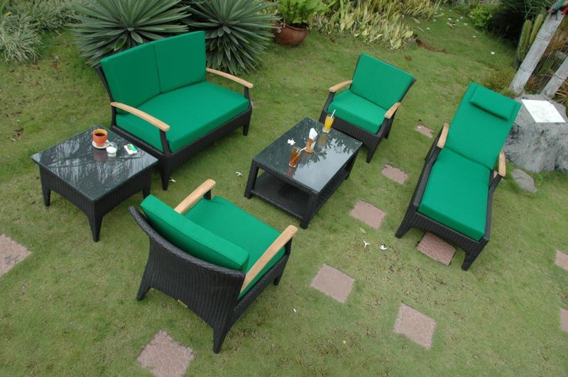 Outdoor furniture set with green cushions on a grassy area