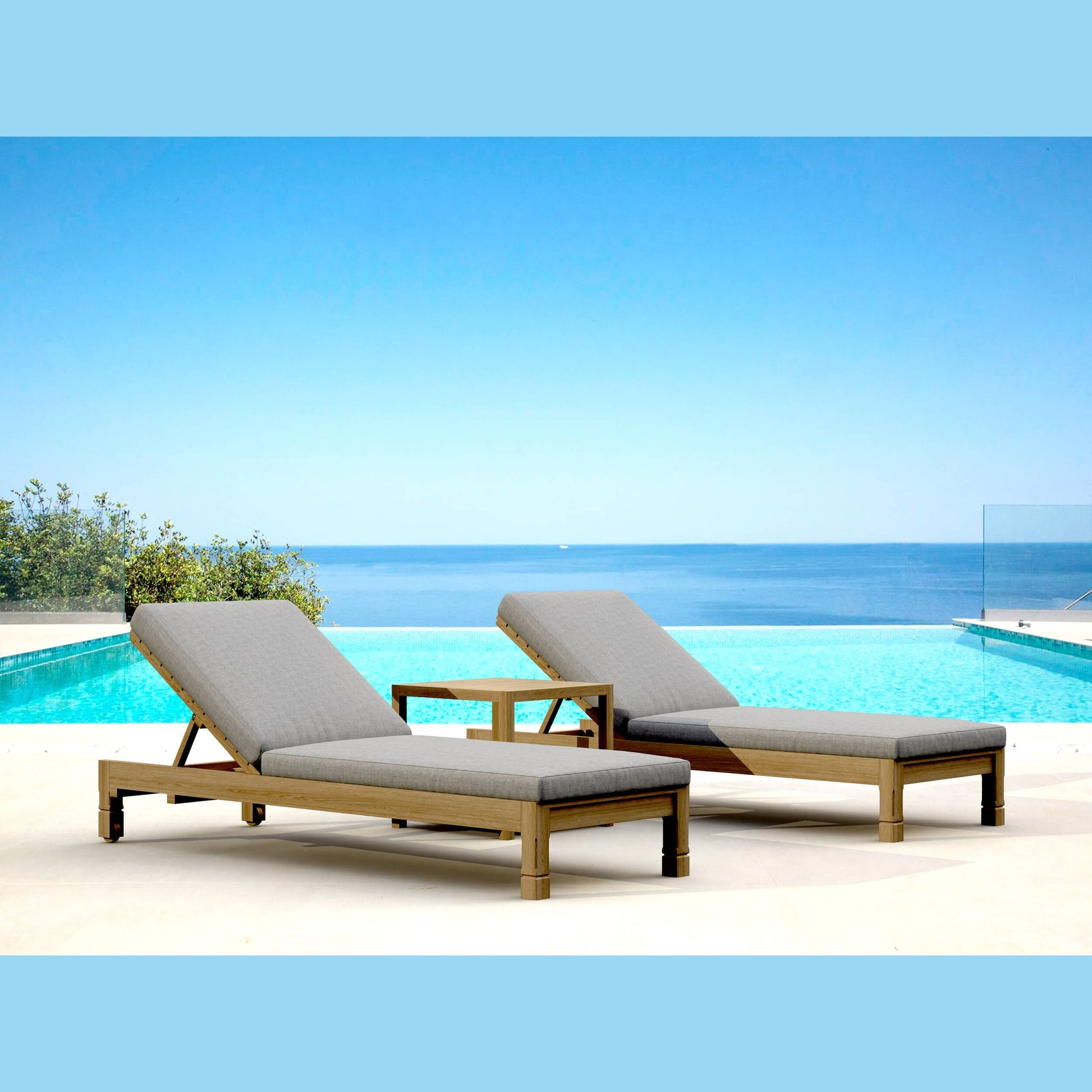 Two lounge chairs with gray cushions by a pool with a clear blue sky and ocean view.