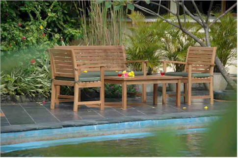 Wooden outdoor furniture set by a pool with greenery in the background