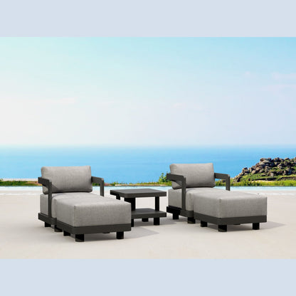 Outdoor patio furniture set with gray cushions and a small table on a sandy beach.