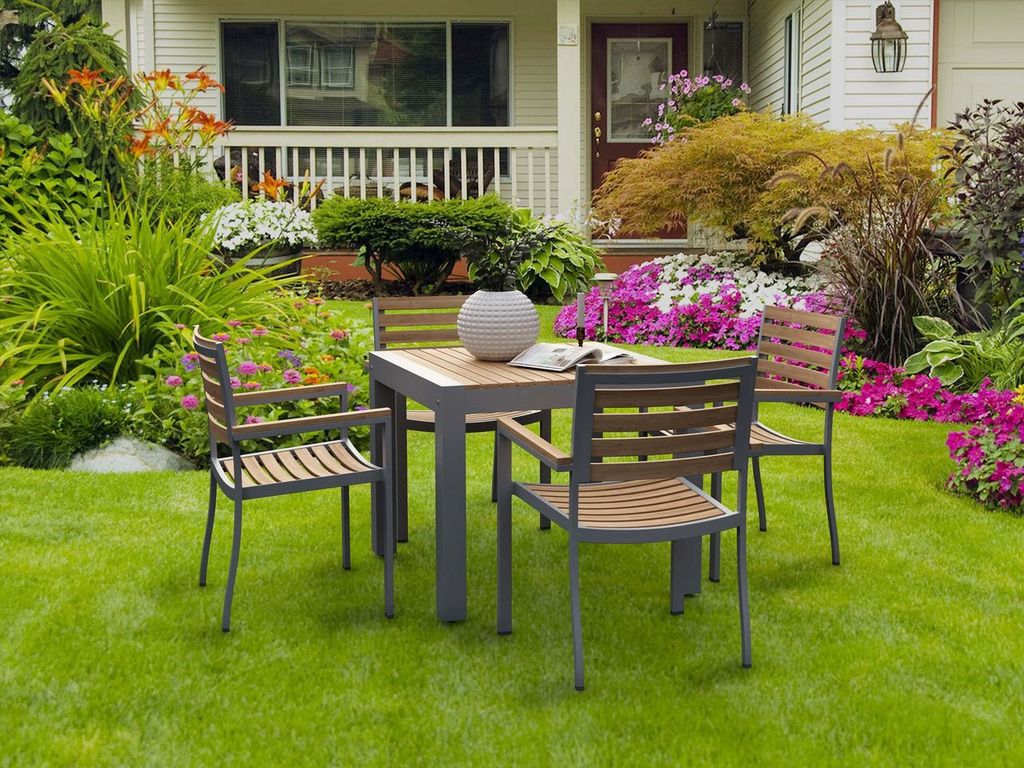 Outdoor patio set with table and chairs on a grassy lawn in front of a house.